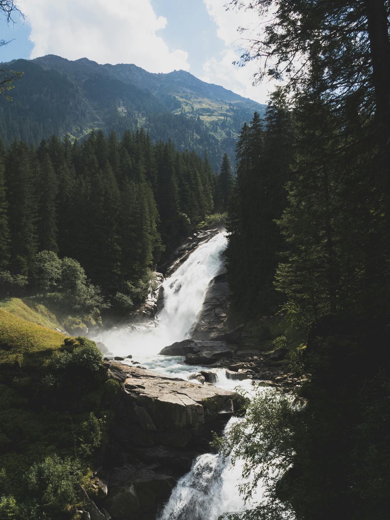 A mountain waterfall flowing through a forest landscape